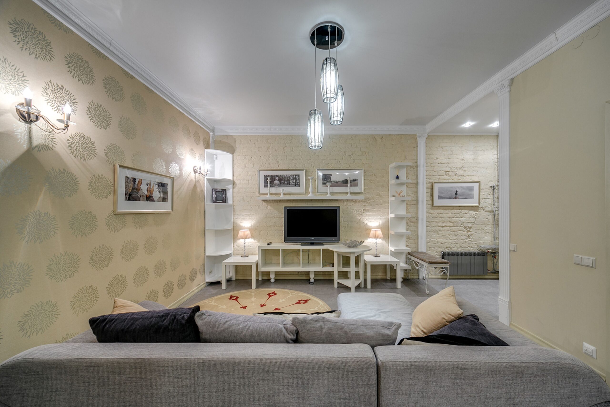 Warm layered living room lighting with floor lamp, reading lamp, and accent shelf light creating cozy evening ambianc