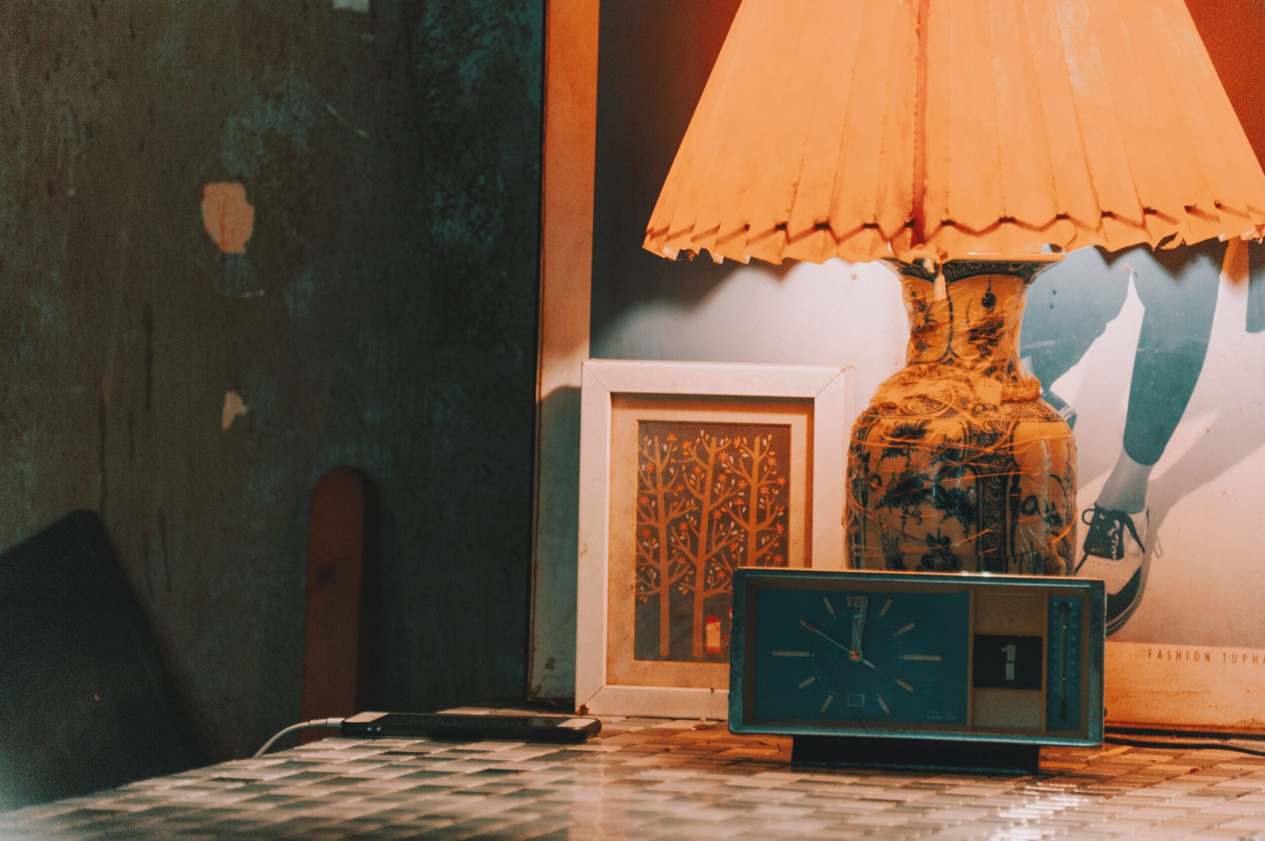 Living room lamp dimmed very low casting soft minimal warm glow on book and side table in quiet evening setting
